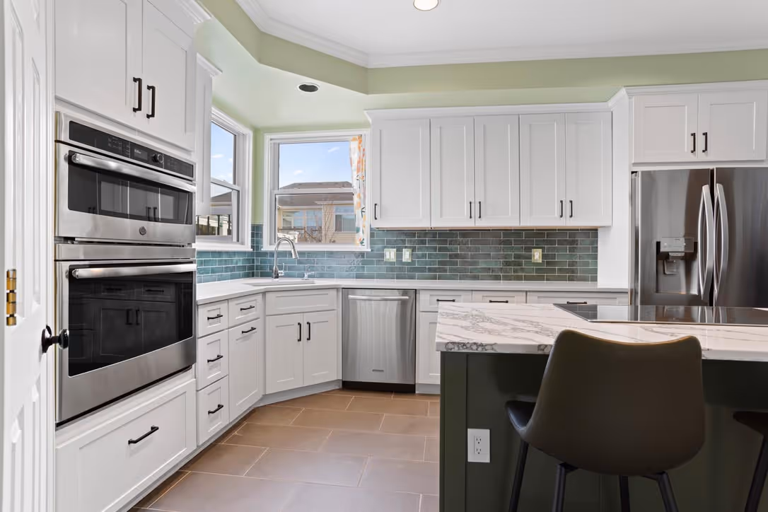 Before and after comparison of a kitchen cabinet transformation from wood to white paint.
