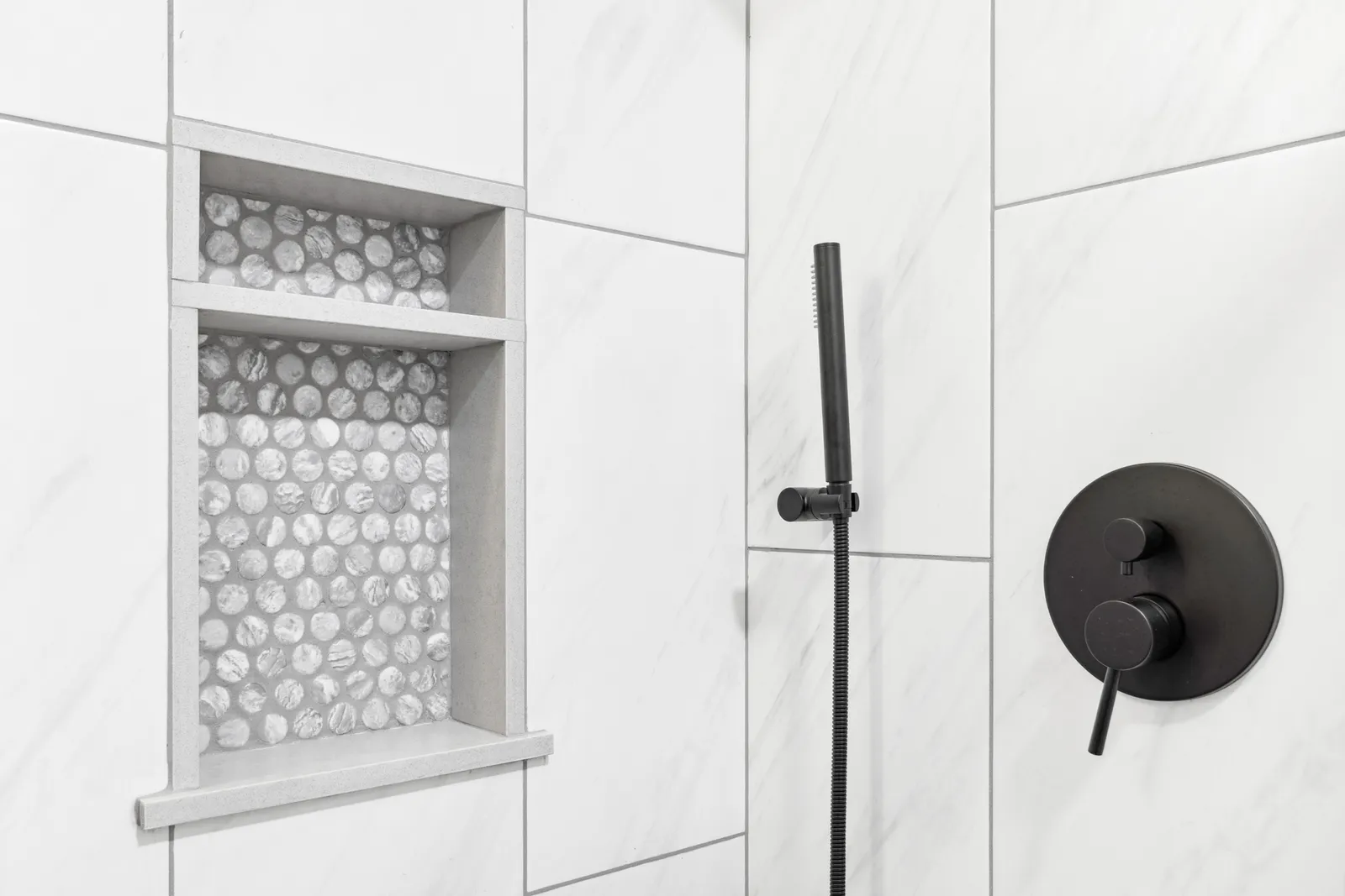 Marble-look tile shower in a remodeled Englewood bathroom