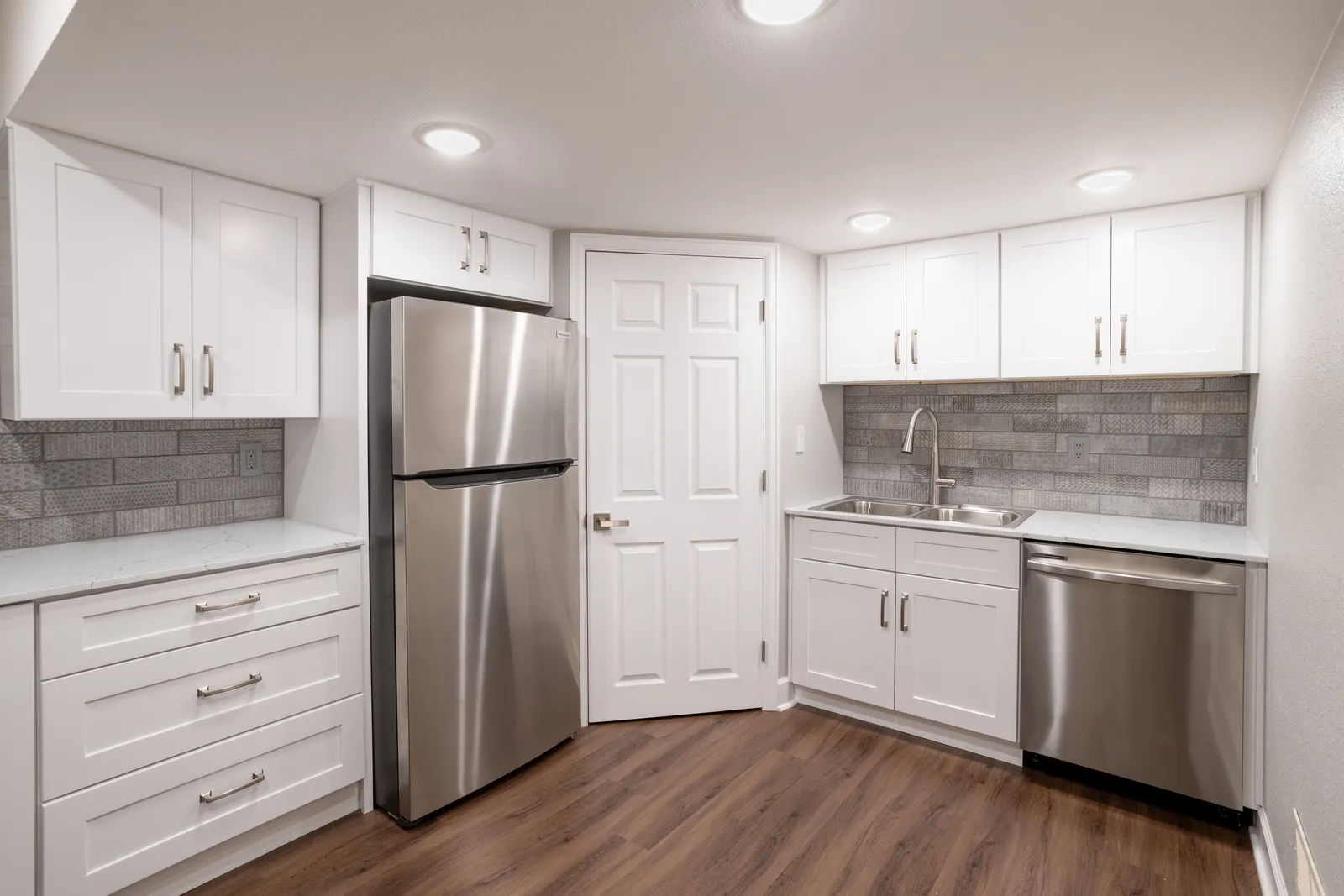 White shaker kitchenette cabinetry with brick backsplash, Centennial